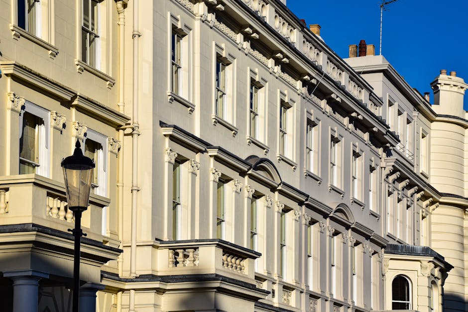 A detailed, upward-looking view of a historic, multi-storey residential building with cream-colored facades and decorative architectural elements, including ornate window frames and cornices, situated